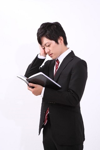 頭を抱えるスーツ男性