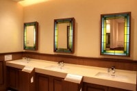 洗面台。さわやかなミントブルーとグリーンのステンドグラスに縁取られた鏡が並びます。