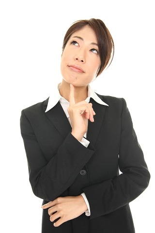 あごを押さえて悩んでいるスーツ女性