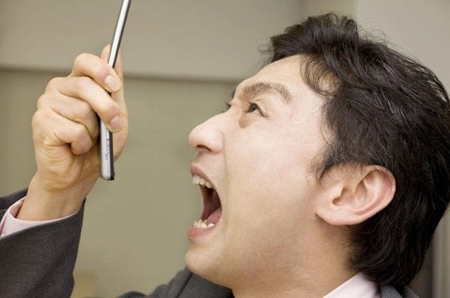 携帯を見て驚いているスーツ男性