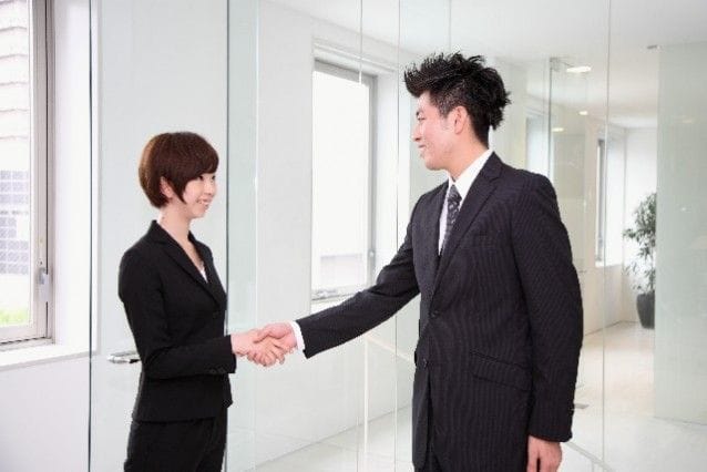 握手をしているスーツ男女
