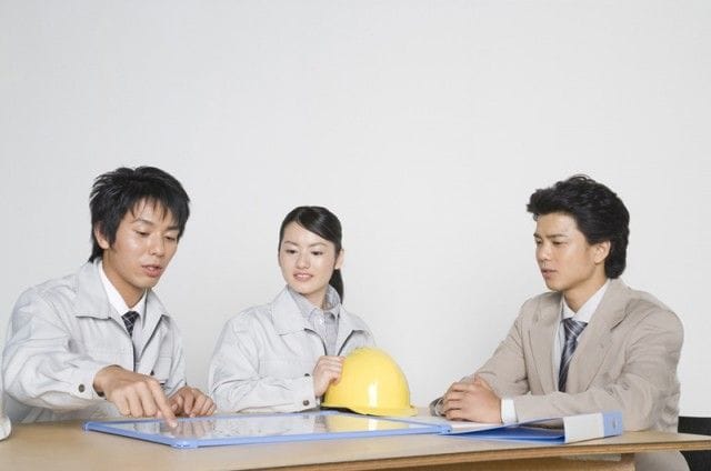 会議で話す建築作業員3人