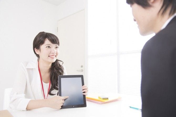 スーツ男性にタブレットを見せる女性