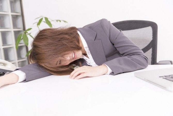 机にうつぶせっている女性
