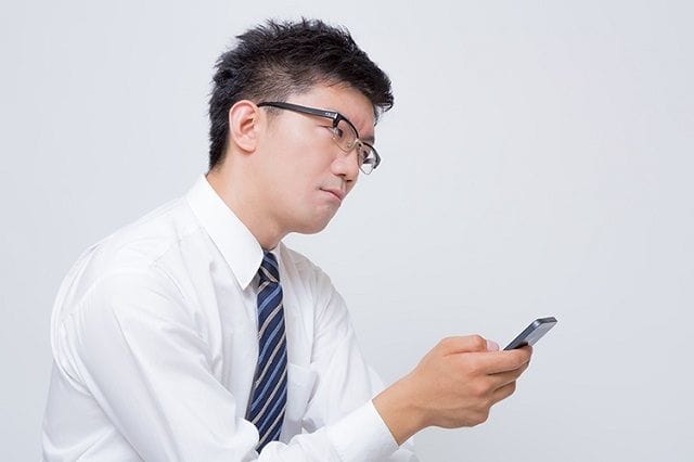 スマホを触りながらにらんでいる男性