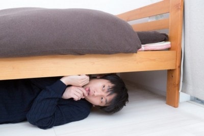 ベッドの下に隠れる男性