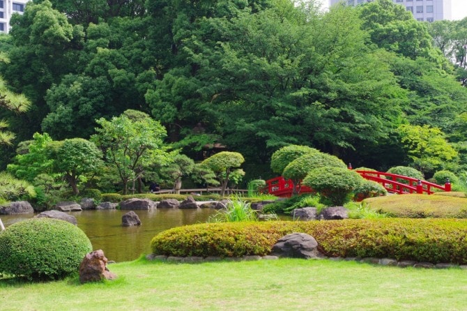 緑に映える、朱色の太鼓橋がアクセントの日本庭園。
